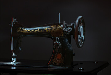 A vintage sewing machine with gold and black embroidery. The machine is turned off and is sitting on a table