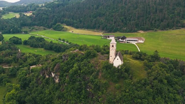 Chiesa di Santa Verena beside meadows and a farmstead, aerial view. Rural church setting in the Province of Bolzano, South Tyrol