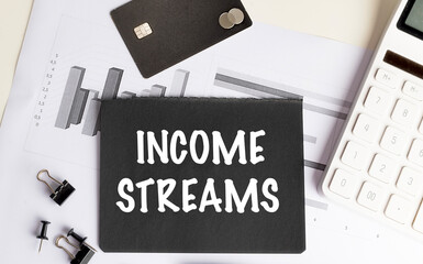 INCOME STREAMS text on black card with charts, calculator, credit card and office supplies on desk