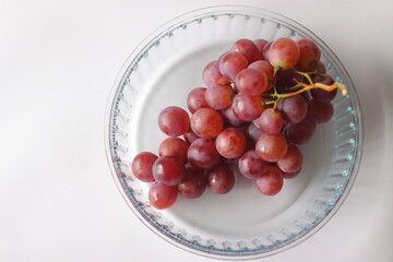 Red table grapes in a clear glass bowl, featuring Red Globe, Crimson Seedless, or Flame Seedless