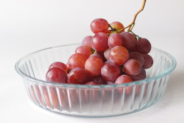 Red table grapes in a clear glass bowl, featuring Red Globe, Crimson Seedless, or Flame Seedless