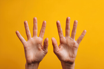 Hands showing surprise reaction with wide open fingers against vibrant yellow background