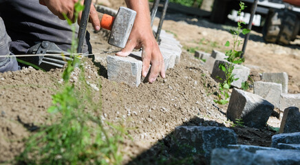 Landschaftsgärtner bei der Arbeit im Detail – präzise Handarbeit im Gartenbau mit Fokus auf...