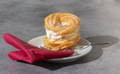 French choux pastry with vanilla filling, custard, and whipped cream. Served in a restaurant at a party. V4.