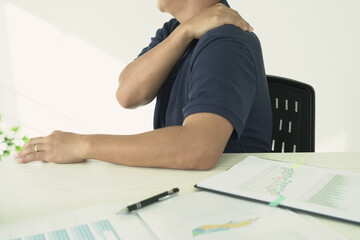 An asian businessman having tensed muscles fatigued, neck, shoulder, back pain during work long time in office, due to fibromyalgia, rheumatism, scapular pain, office syndrome and ergonomic concept.