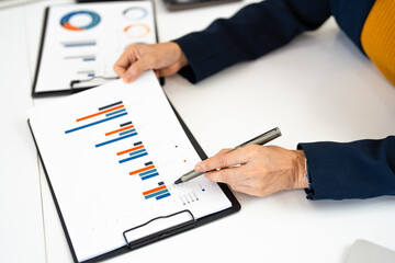 Close up hands reviewing financial charts and documents in office desk. analyzing business charts statistic marketing data, working on financial business plan for startup.
