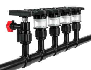 Close-up of a complex black plastic irrigation system with a red valve, staged against a black background