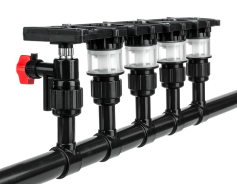 Close-up of a complex black plastic irrigation system with a red valve, staged against a black background