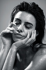 Studio closeup photo of a woman with natural makeup, wet hair, and sparkling glitter on her skin. The image evokes a sensual, artistic, and glamorous mood.