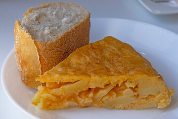 Close-up of a Spanish omelette skewer on a blueish concrete table. Top view highlighting the texture of the tortilla de patatas, traditional Spanish cuisine