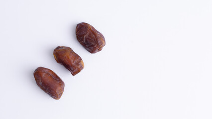 Minimalist Flat Lay of Three Sukkari Dates with Copy Space. Sweet Ramadan fruit for healthy, energy-boosting promotions.
