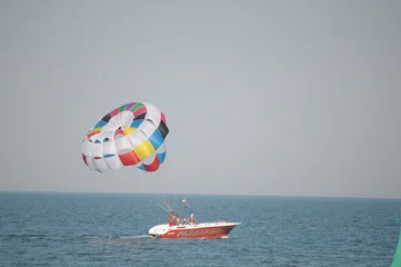 Fototapete Extremsportarten Colorful parasailing adventure over blue ocean water  © buFka