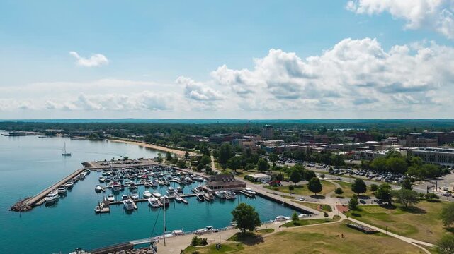 Aerial view, timelapse, of Traverse City, Mi.  Shot in 4k with DJI Air3s, 200 still images at @23.976fps creating 8 seconds.  Drone is moving south east towards clinch marina with beautiful clouds.