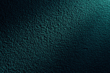 ターコイズグリーンの光に浮かぶざらざらした土壁のテクスチャー