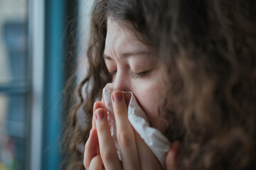 Sick woman blowing nose at home, cold flu allergy symptoms health care concept