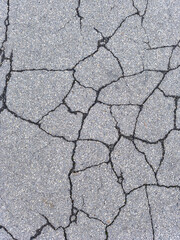 Close-up of cracked asphalt surface, showing texture and damage details