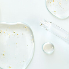 Transparent liquid serum with gold flakes and dropper on white background for skincare.