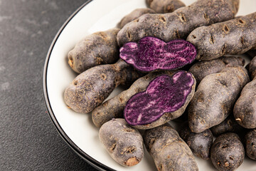 Purple potatoes raw fruit blue potatoe vegetable dish fresh gourmet food background on the table rustic food top view copy space keto and paleo diet vegan and vegetarian food
