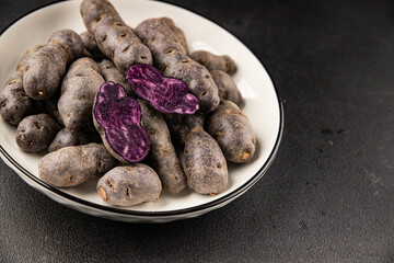 Purple potatoes raw fruit blue potatoe vegetable dish fresh gourmet food background on the table rustic food top view copy space keto and paleo diet vegan and vegetarian food