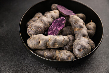 Purple potatoes raw fruit blue potatoe vegetable dish fresh gourmet food background on the table rustic food top view copy space keto and paleo diet vegan and vegetarian food