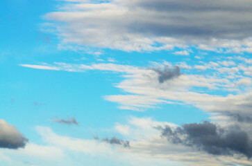 Dramatic sky with clouds in shades of gray and white against a bright blue background