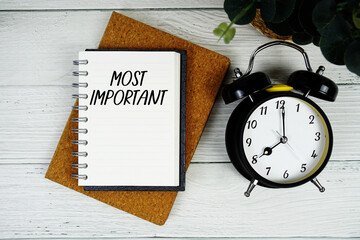 Most Important text written on notepad with alarm clock on wooden background © may1985