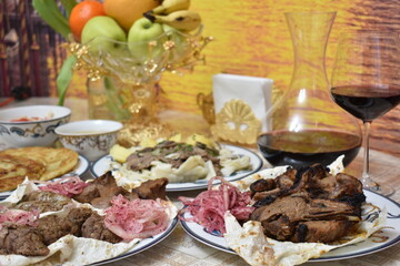 Assorted grilled meat, beshbarmak, red wine in a glass decanter
