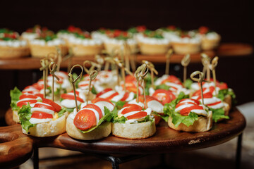 Mini tomato and cream canapes on wooden serving board with decorative toothpicks