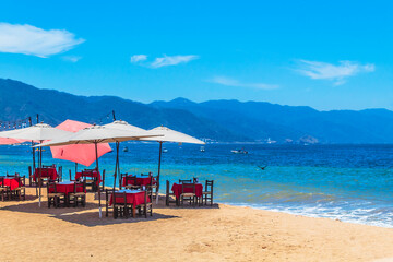 Chairs with tables under umbrellas on the beach facing the sea, in Puerto Vallarta, Jalisco