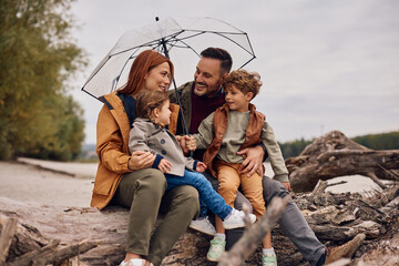 Happy family talking while relaxing in nature in autumn.