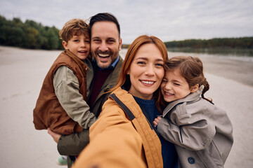 Happy family having fun while taking selfie in autumn day in nature.