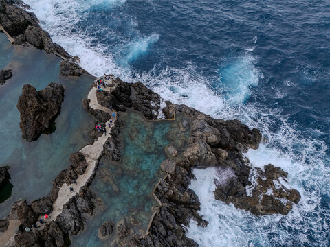 Fototapeta Aerial view of natural lava pools and coastal village in Porto Moniz, Madeira, surrounded by dramatic cliffs and Atlantic waves. 