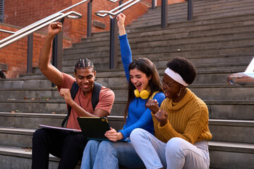 Diverse students celebrating success looking at tablet