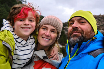 Happy family in warm clothes taking selfie in nature.