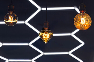 A decorative incandescent light bulb hangs from a dark ceiling.