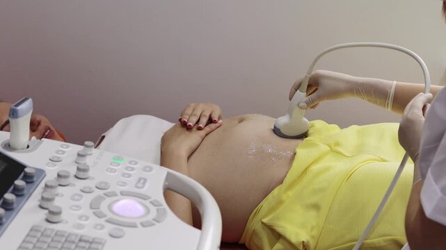 Pregnant woman on ultrasound examination at hospital 4k video. Pregnancy health checkup with ultrasound equipment.