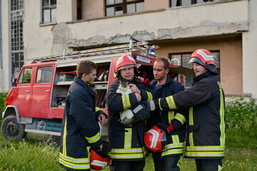 Fototapeta premium Firefighters rescuing a cat near a fire truck, showcasing teamwork and compassion, with focus on animal rescue and emergency response in an outdoor setting, featuring brave firemen.