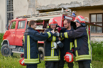 Fototapeta premium Firefighters rescuing a cat from a fire, team of firemen with a rescued kitten, fire truck in the background, teamwork and compassion, outdoor scene, emergency response