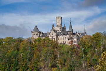 Marienburg Castle - Gothic revival castle in Lower Saxony, Germany. A Scenic Castle That Gracefully Overlooks a Lush Green Valley Surrounded by Nature in autumn.