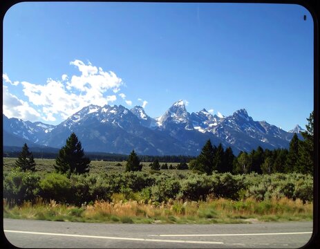 Scenic view of mountains with snow-capped peaks and blue sky on a sunny day - Powered by Adobe