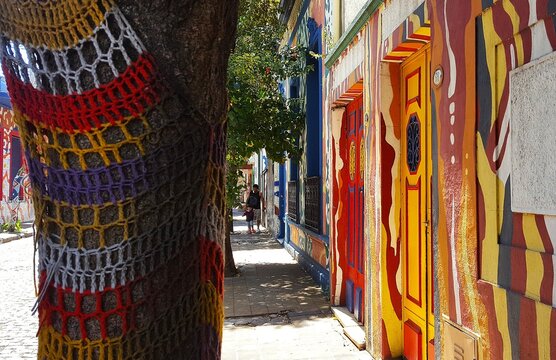 Vecino camina tranquilo por una vereda con &aacute;rboles decorados con tejidos hechos a mano en el antiguo y tradicional barrio de Barracas en Buenos Aires, Argentina 