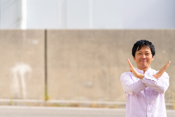 手でバツ印を作る笑顔の男性｜「NO」を伝えるジェスチャー