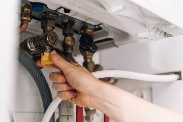 Repairman fixing modern boiler in utility room with a wrench and tools