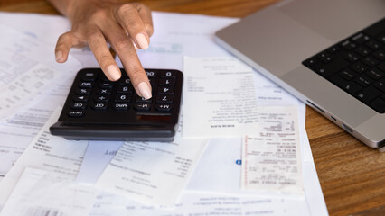 Hands of woman counting monthly expenses, using calculator