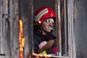 Brave firefighter in red helmet rescuing a child from a burning building, fire rescue operation,...