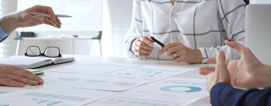 Business meeting with colleagues discussing financial charts, strategy planning, and analyzing data reports during a professional teamwork collaboration session - Powered by Adobe