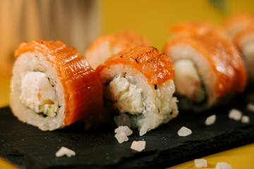 Fresh salmon sushi rolls served on a black slate with sea salt at a vibrant restaurant