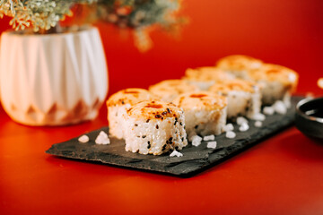Sushi rolls arranged on a black slate plate with a vibrant red background