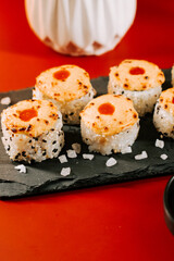 Delicious sushi rolls served on a black slate plate with a vibrant background