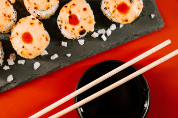 Delicious sushi rolls served on a slate plate with soy sauce and chopsticks